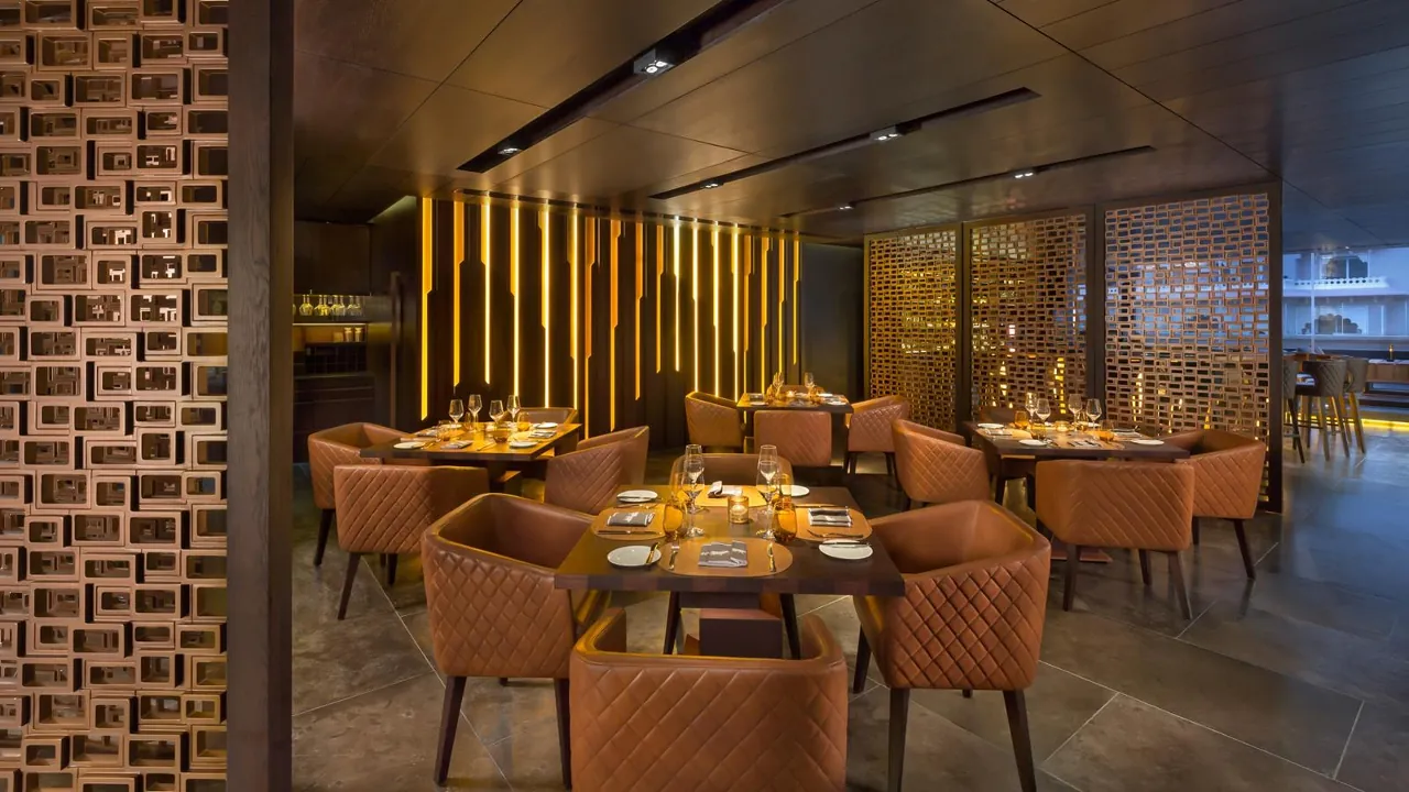 Rib Room dining room with chandeliers, wall lights, and dark red seating
